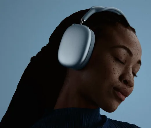 Frau trägt die AirPods Max 2 in Blau vor dunkelblauem Hintergrund